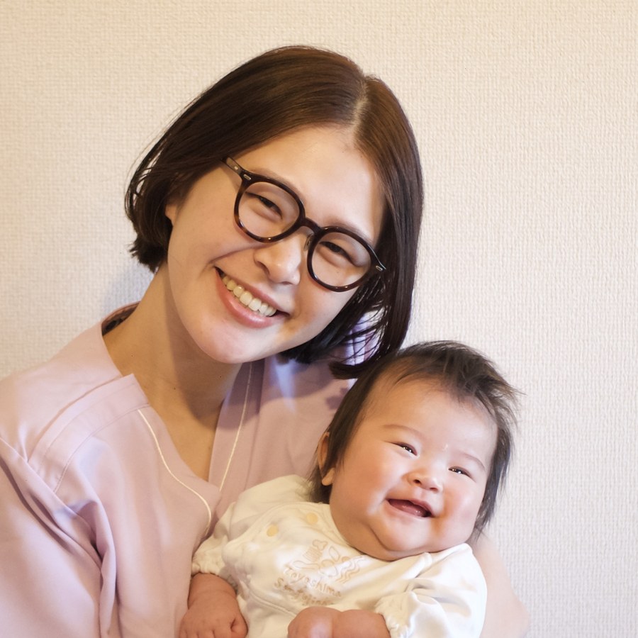 国家資格を持つ助産師が笑顔で赤ちゃんを抱く様子