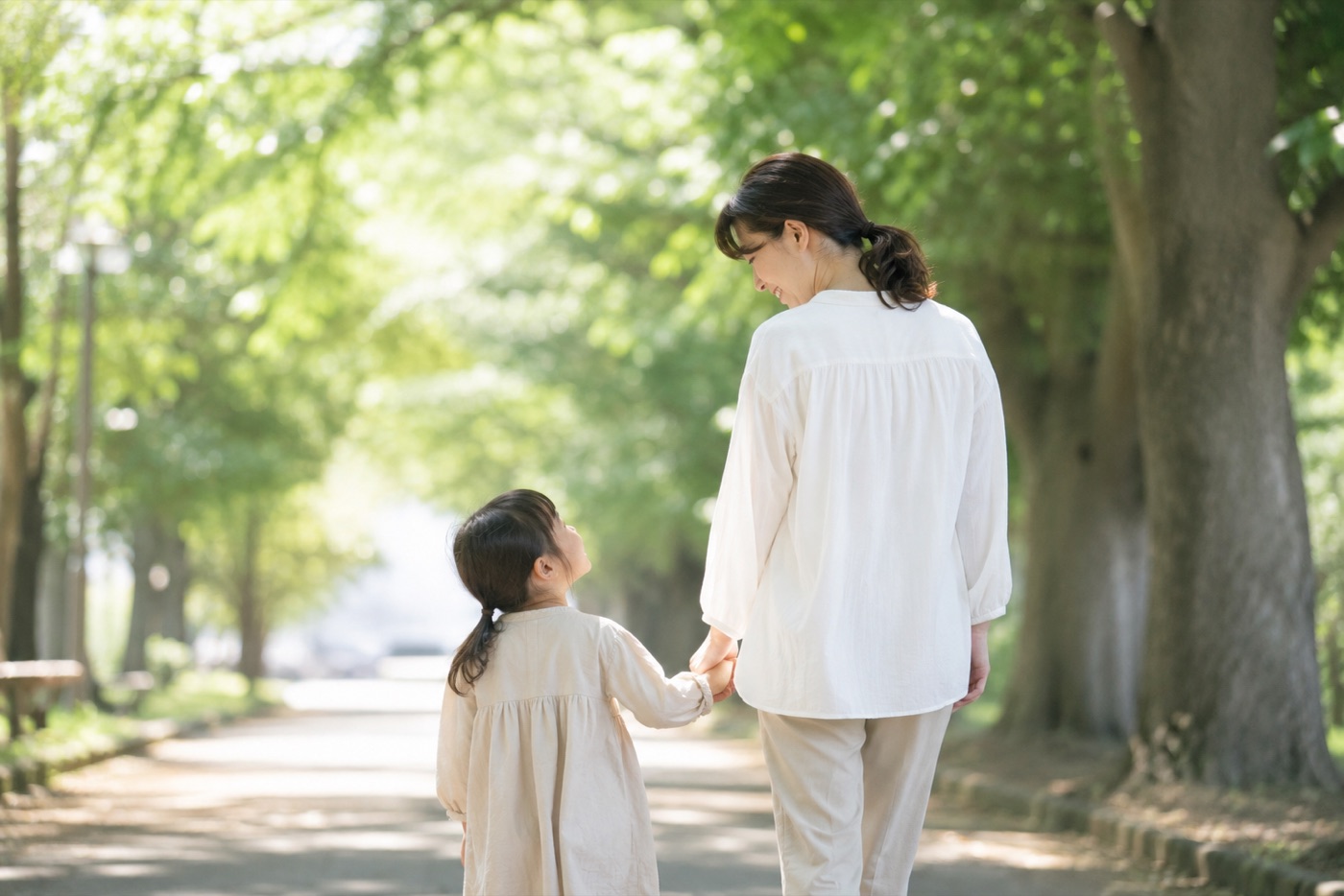 並木道を手をつないで歩くお母さんと上のお子さま