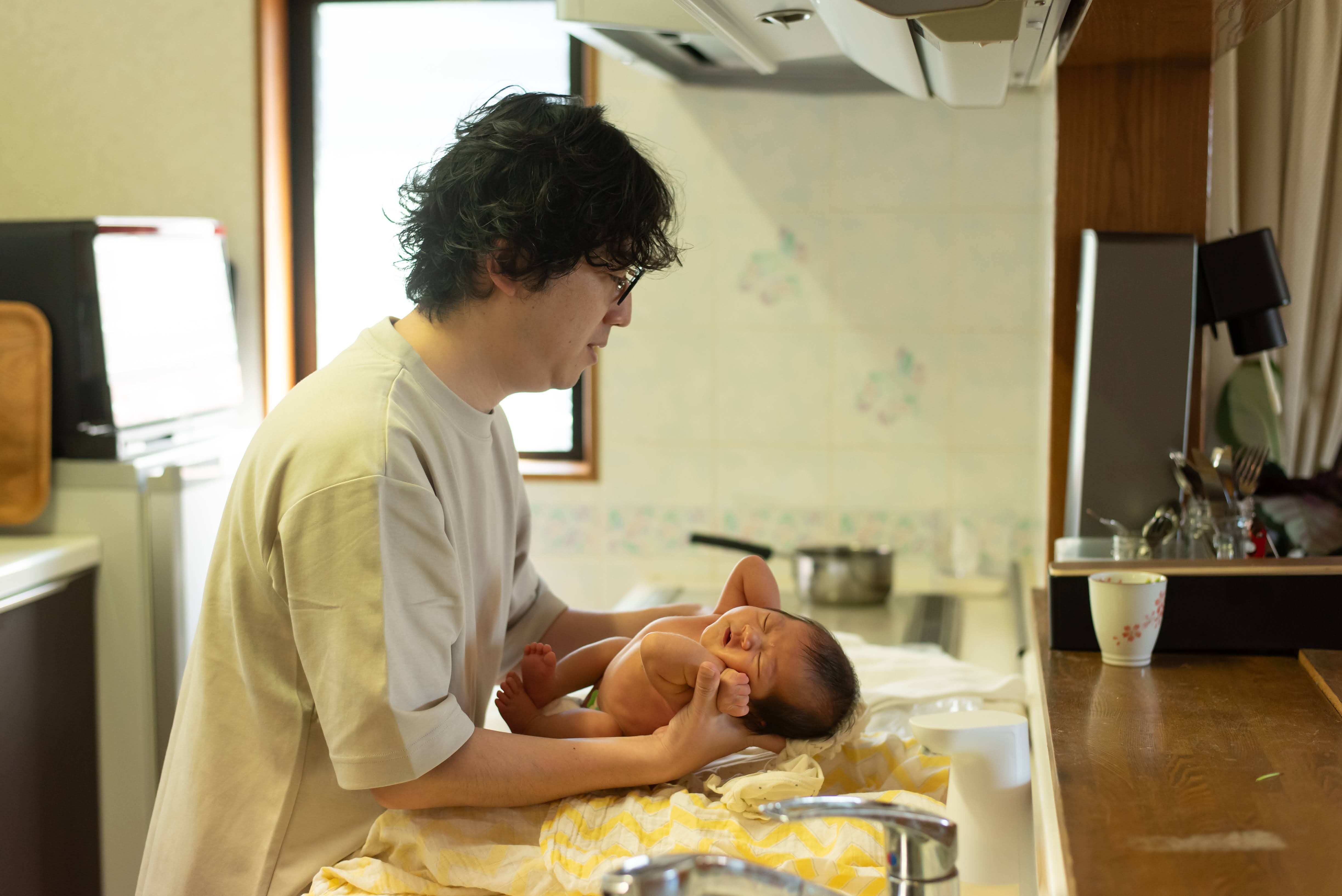 自宅のキッチンで赤ちゃんをやさしく抱く様子