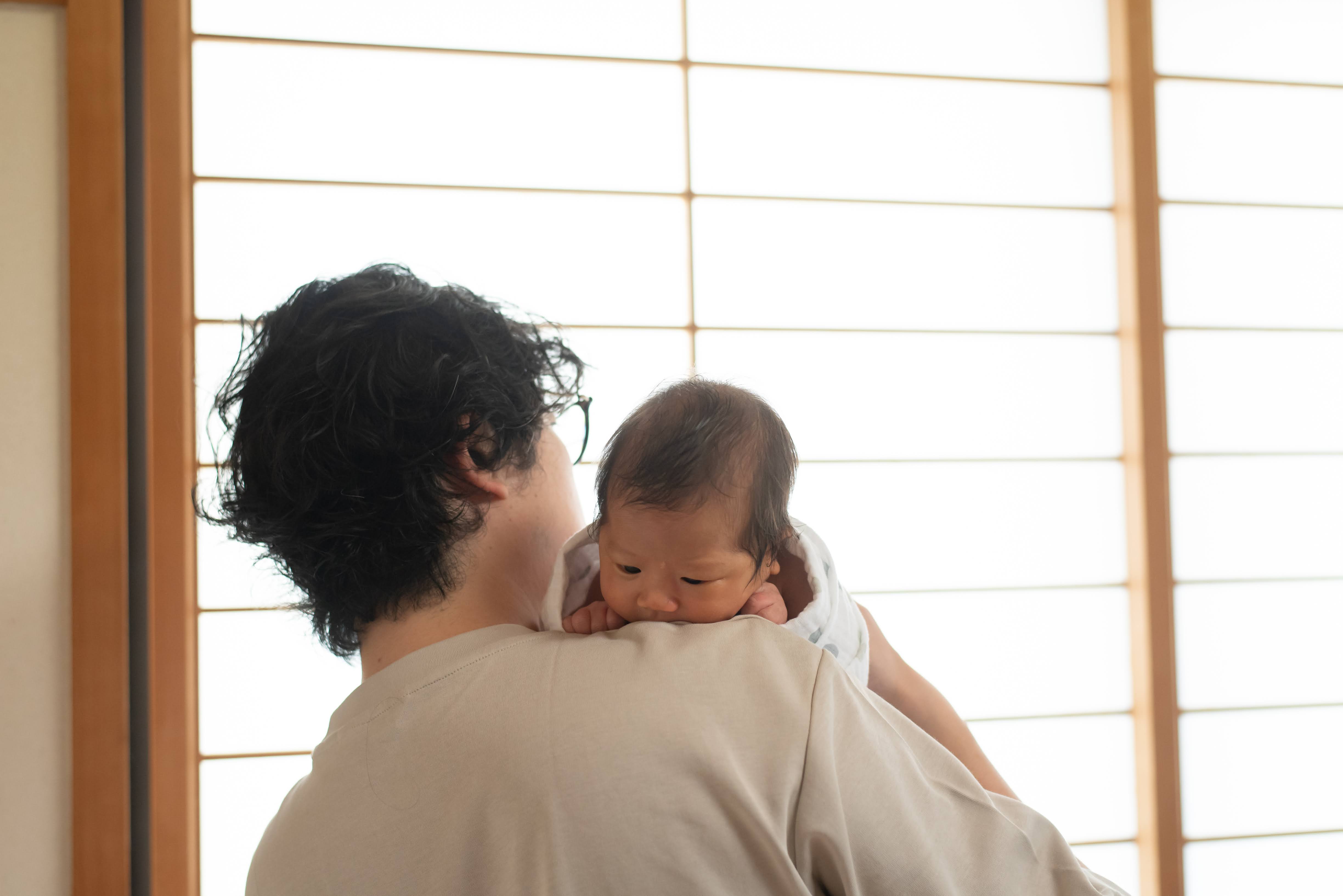障子の柔らかな光の中、赤ちゃんを抱く家族