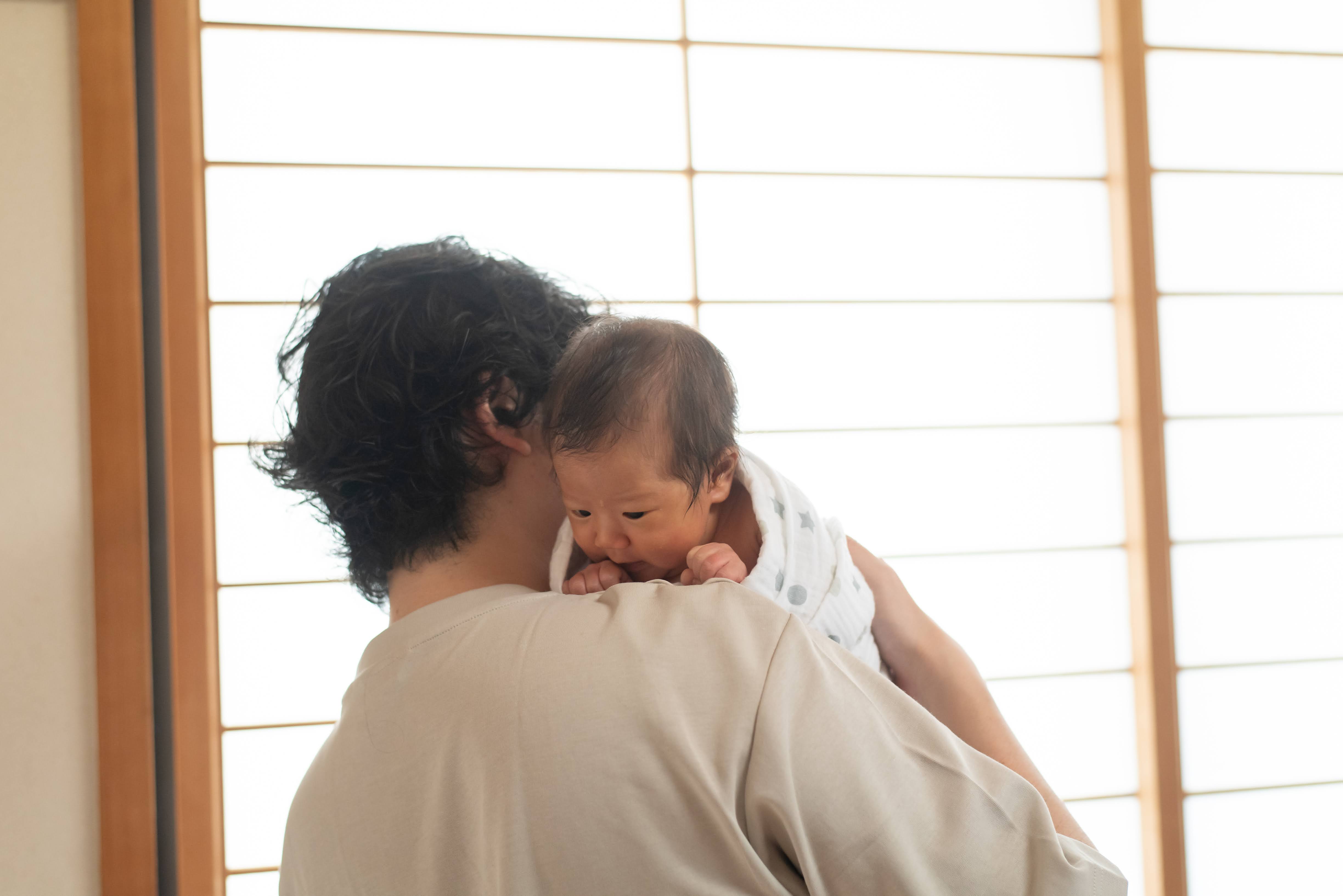 柔らかな自然光の中、赤ちゃんを抱く家族のひととき
