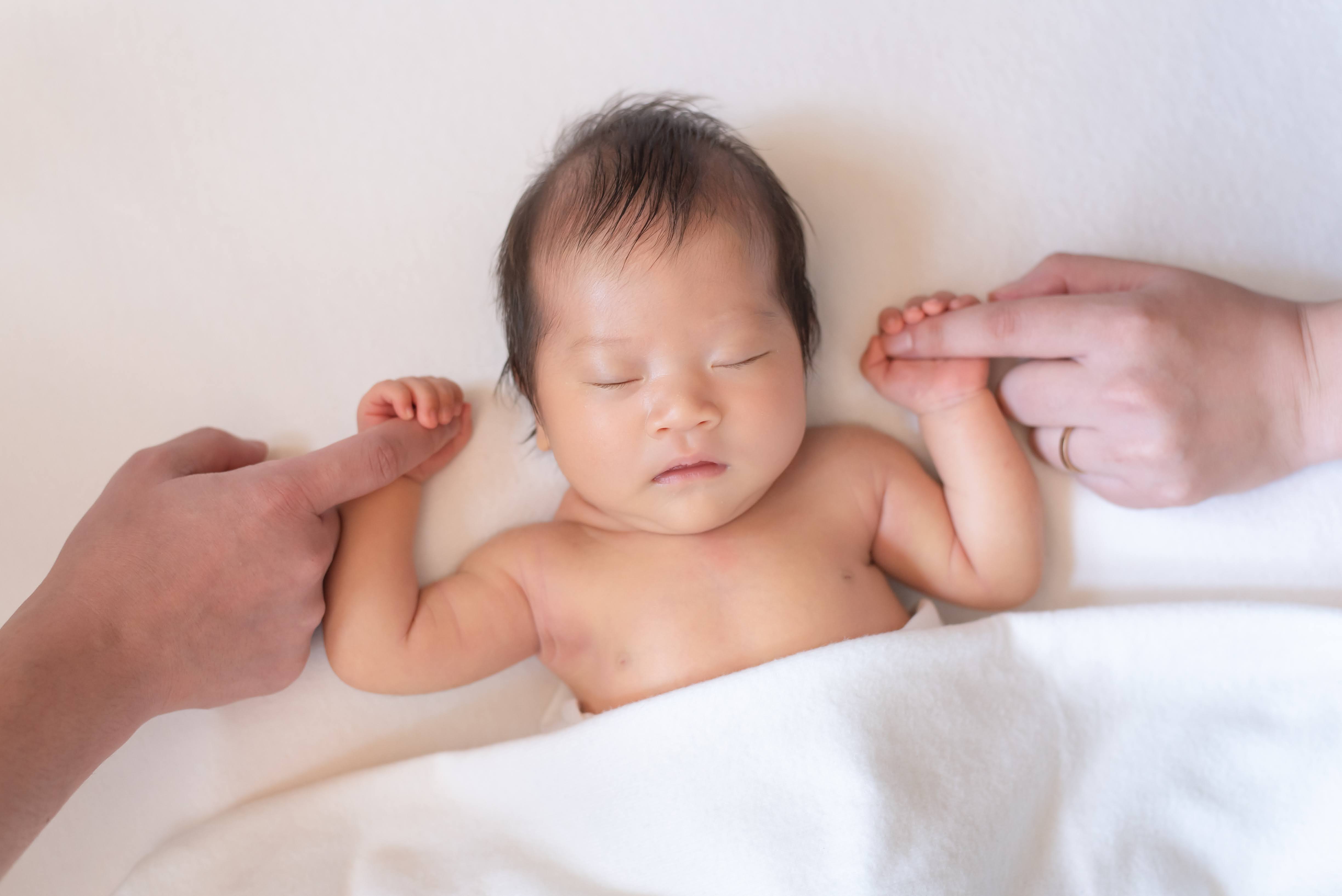 白を基調とした落ち着いた空間で穏やかに眠る新生児